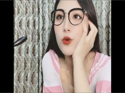 Она носит очки и показывает свою большую грудь.